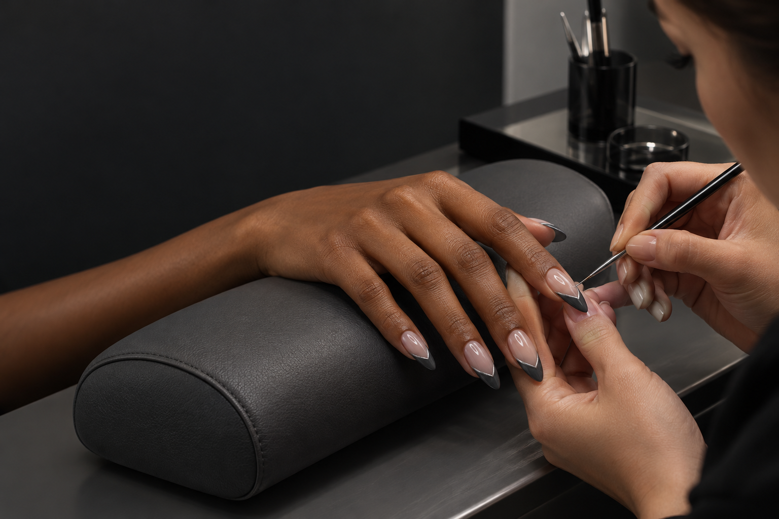 A nail artist refining geometric French tips at a clean contemporary salon workstation